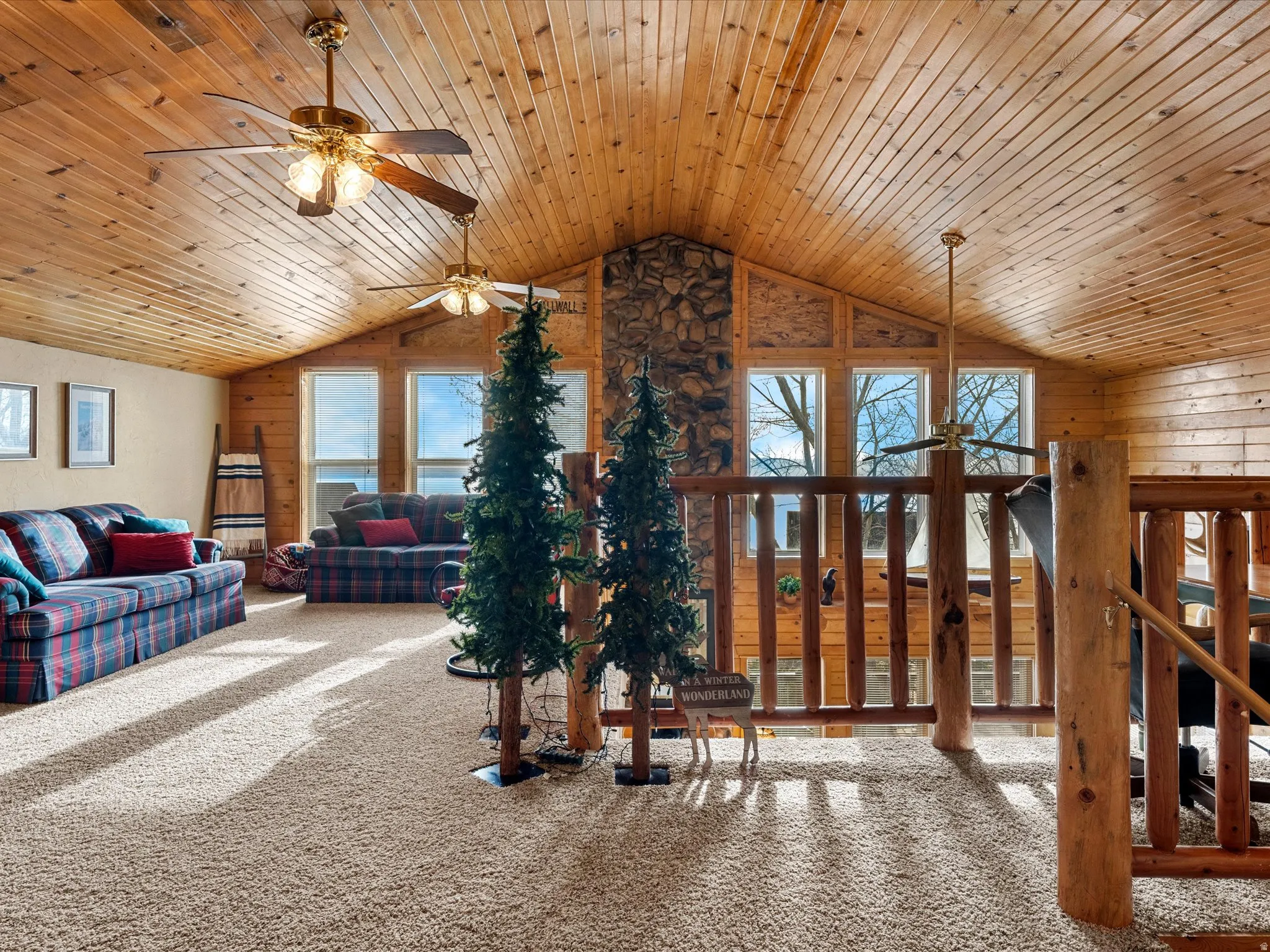 Carpeted living room featuring a ceiling fan, wooden walls, and wood ceiling