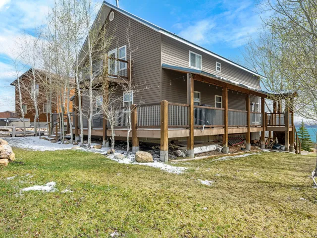 Rear view of house featuring a lawn and covered porch