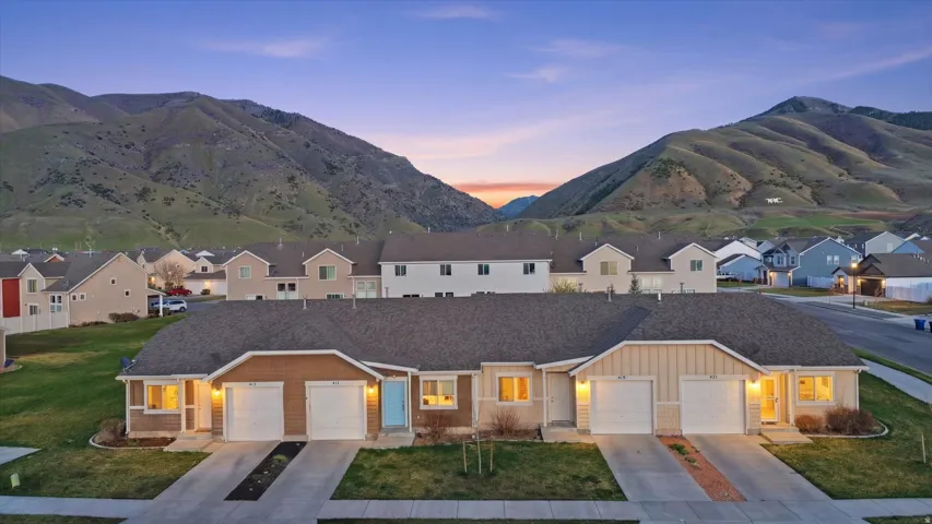 View of front of house with a mountain view, board and batten siding, a yard, and concrete driveway