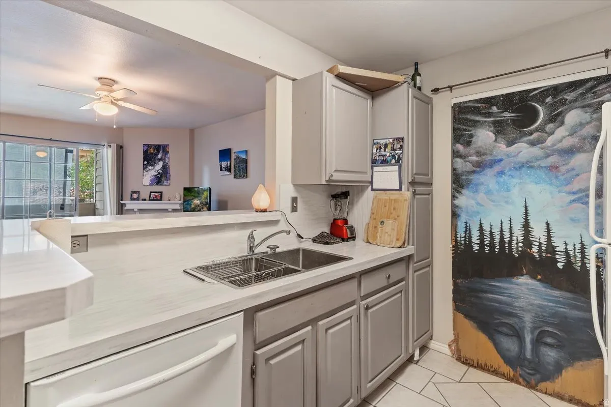 Kitchen featuring gray cabinets, light countertops, white appliances, light tile patterned floors, and ceiling fan