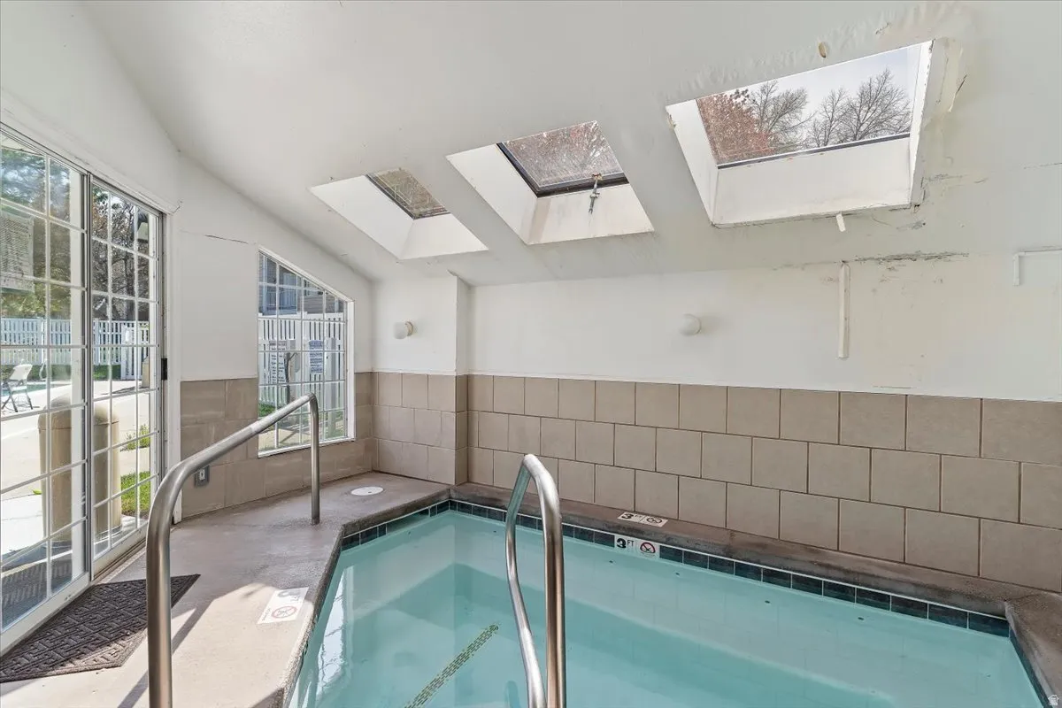 View of pool with a skylight and a hot tub