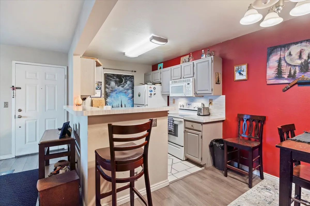 Kitchen with light countertops, a breakfast bar area, white appliances, and light wood-type flooring