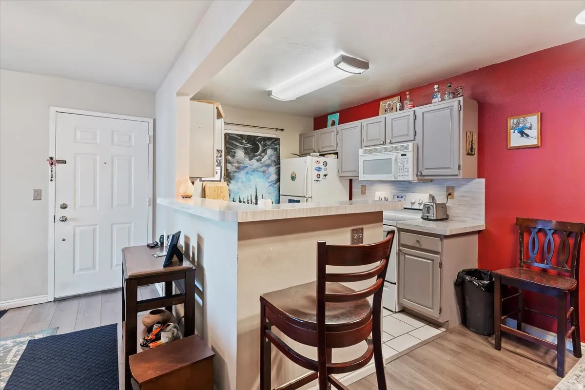 Kitchen with light countertops, backsplash, gray cabinets, and a breakfast bar