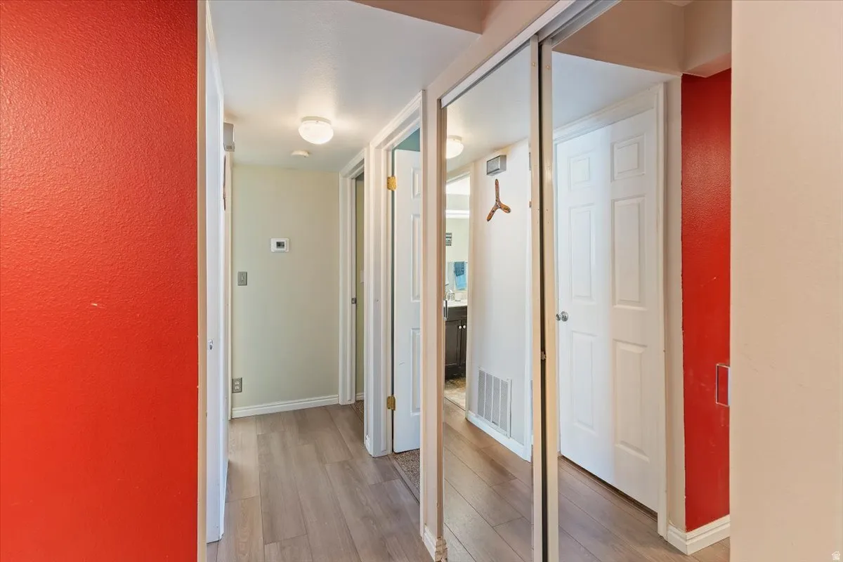 Hallway with light wood-style flooring and a textured wall
