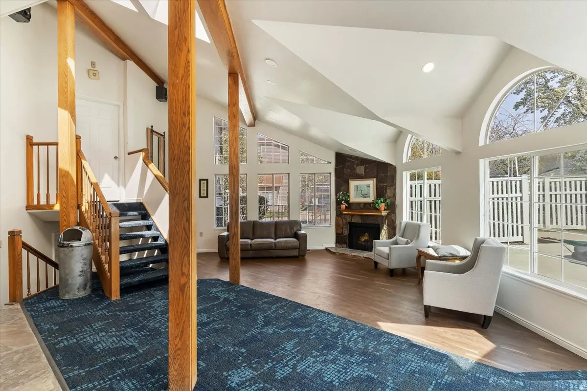 Living room featuring lofted ceiling, a stone fireplace, a skylight, recessed lighting, and wood finished floors