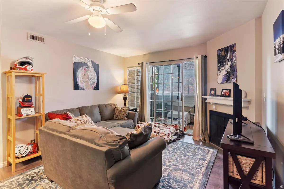 Living room featuring ceiling fan, wood finished floors, and a fireplace