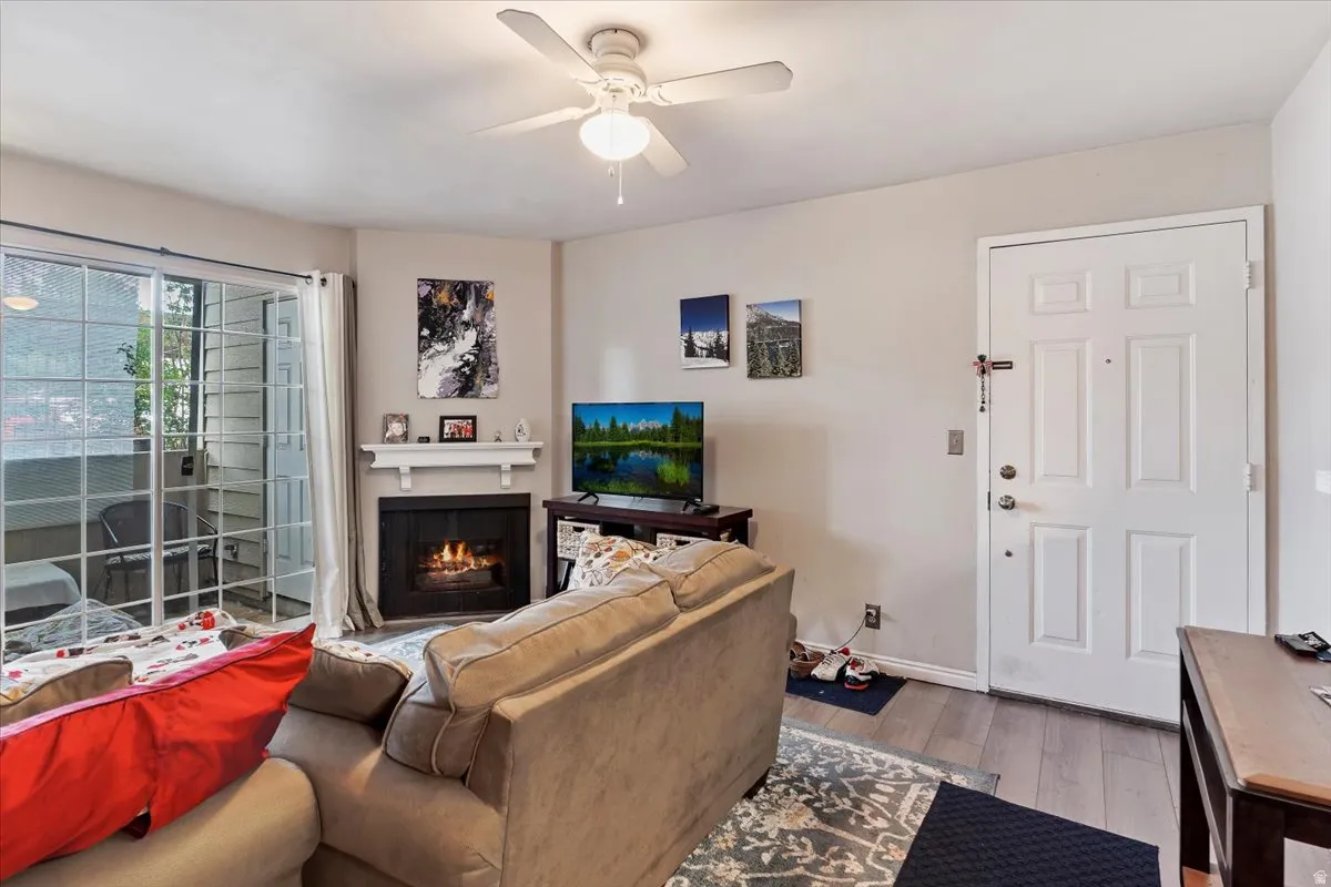 Living room featuring a ceiling fan, light wood-style flooring, and a lit fireplace