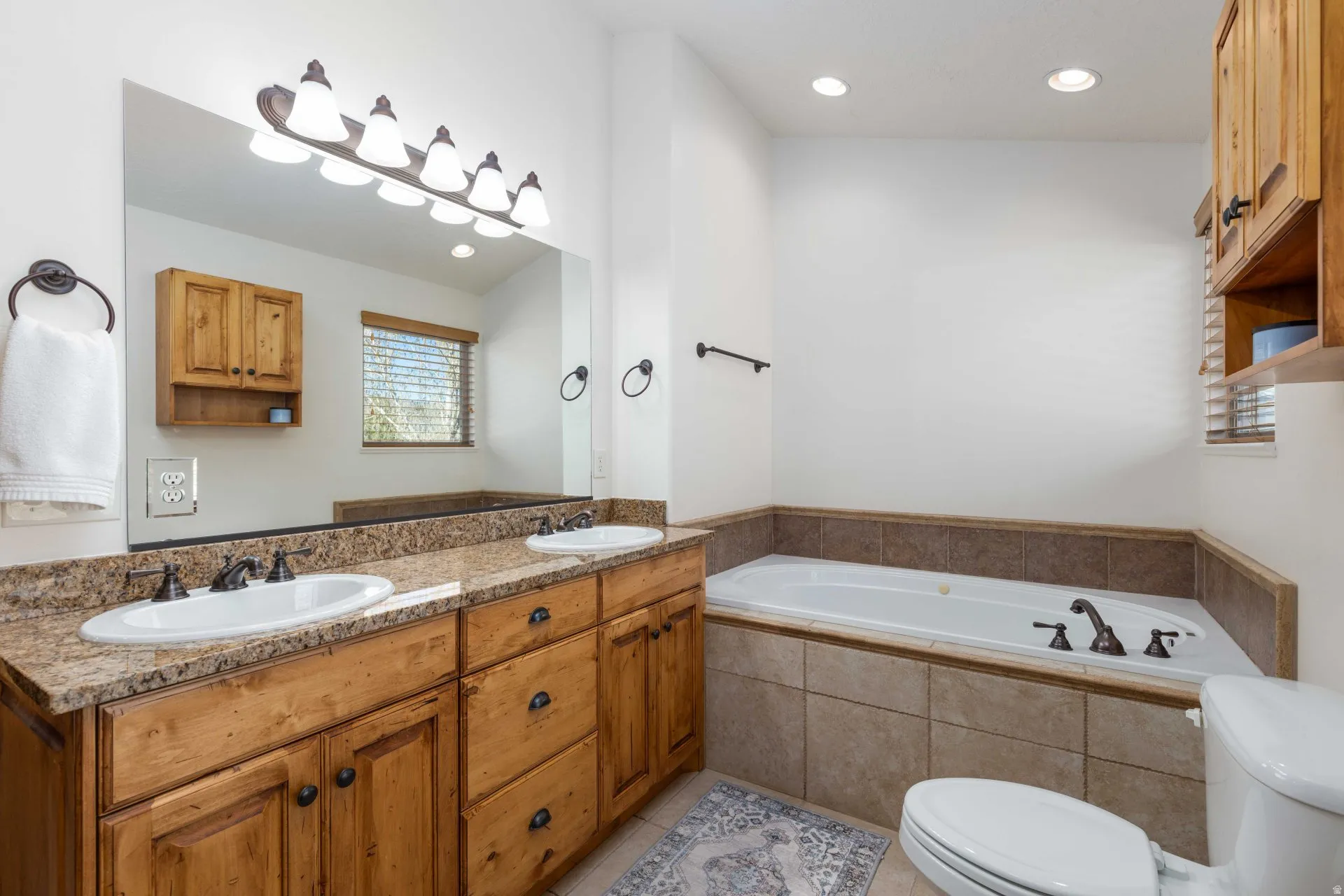 Full bathroom featuring double vanity, a garden tub, recessed lighting, and light tile patterned flooring