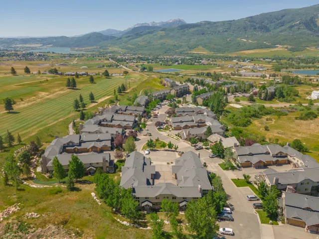 Aerial view highlighting a residential community with multi-family buildings featuring dark gray roofs and light-toned siding