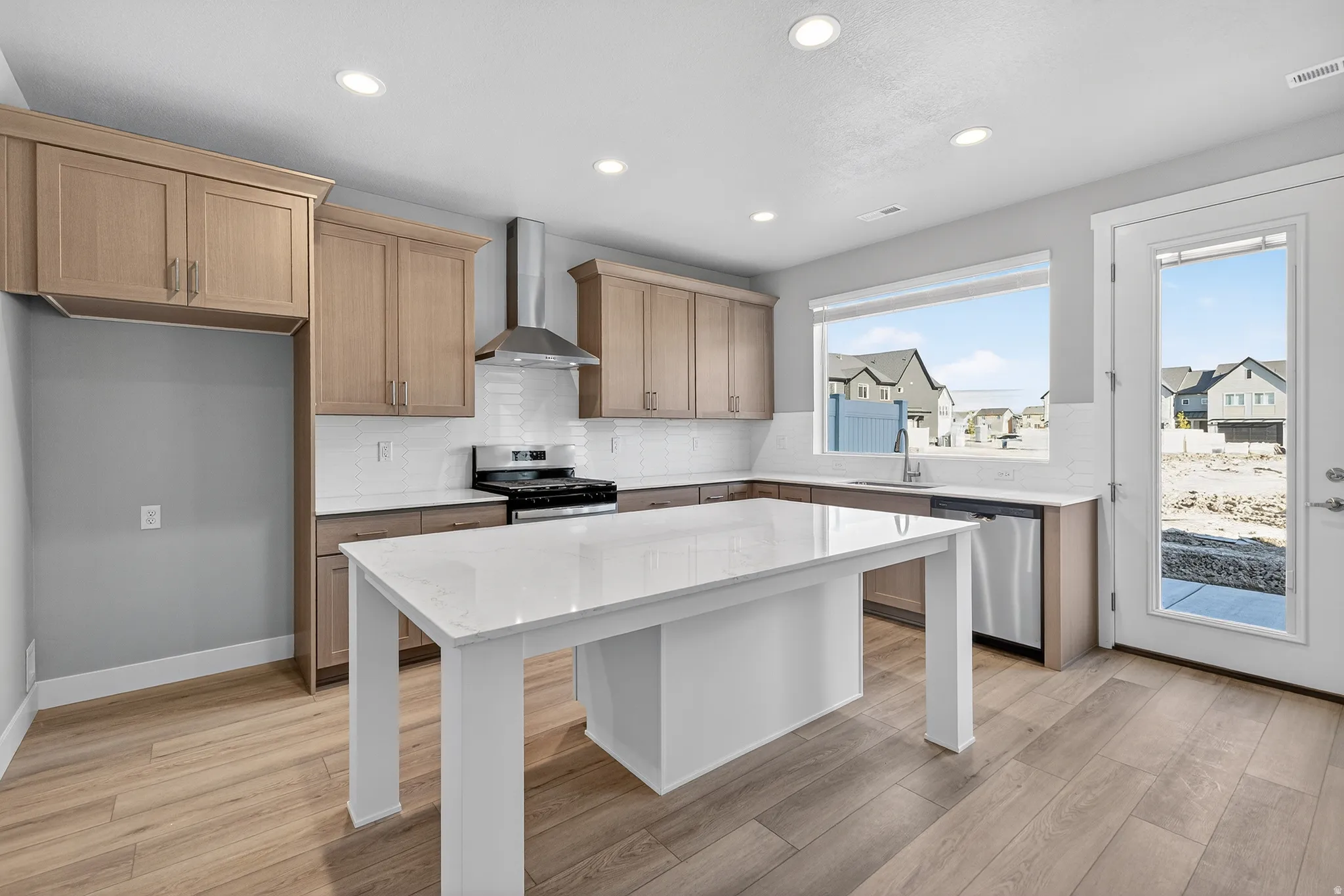 Kitchen featuring decorative backsplash, stainless steel appliances, light stone countertops, light wood-style floors, and recessed lighting