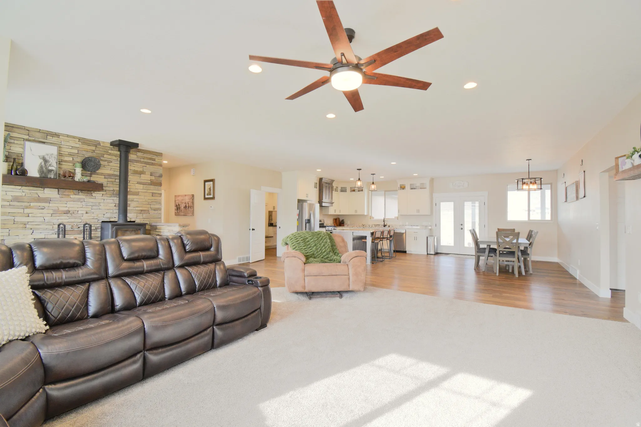 Living area featuring a wood stove, ceiling fan, light carpet, and recessed lighting
