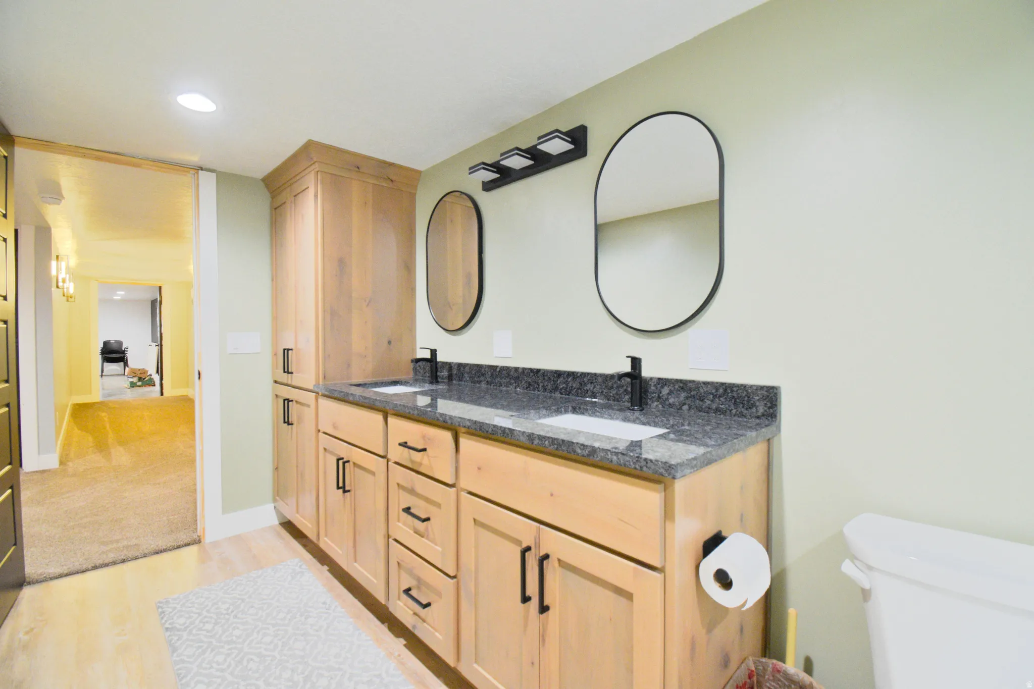 Bathroom featuring double vanity, light wood-type flooring, and recessed lighting