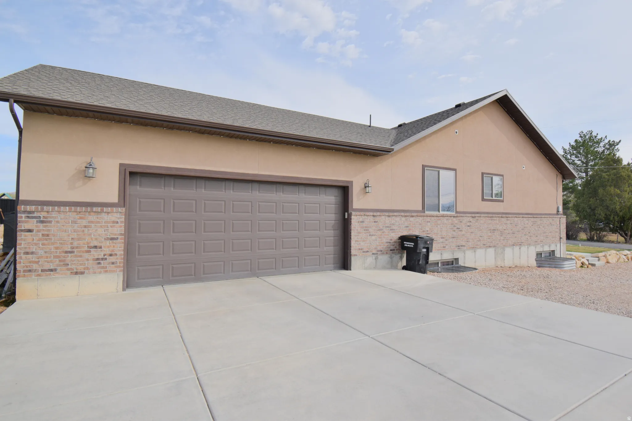 View of property exterior featuring stucco siding, brick siding, driveway, and a garage