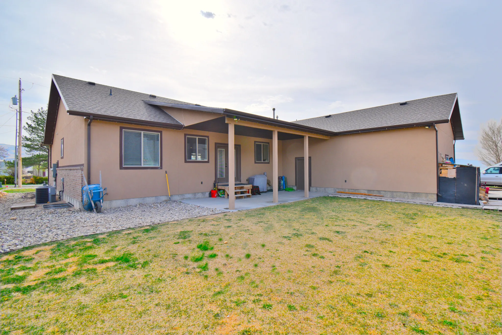 Back of property with a patio, a lawn, stucco siding, and a shingled roof