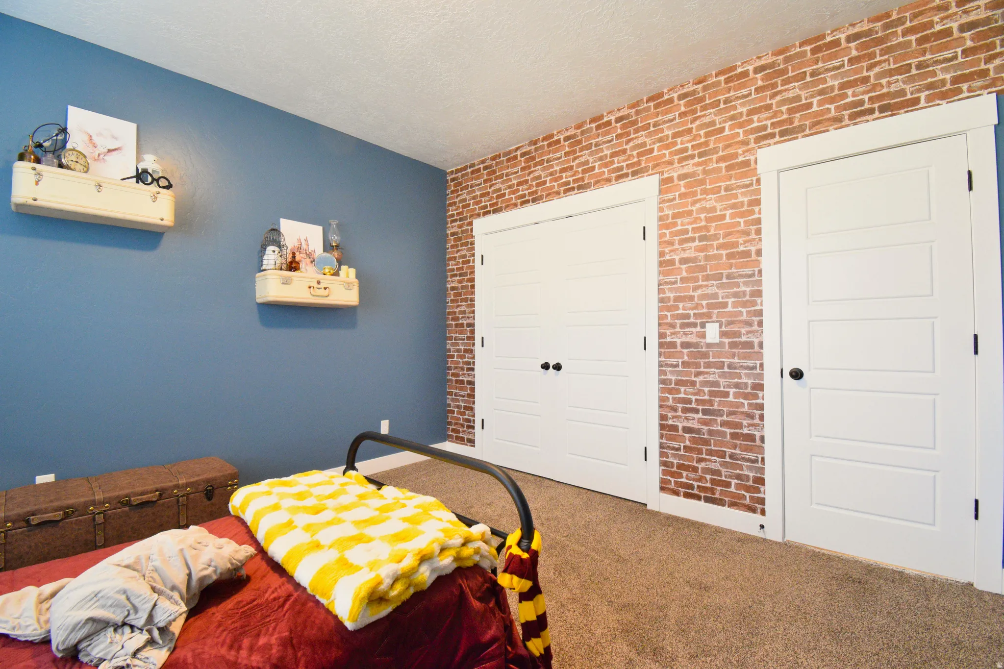 Bedroom featuring a closet, brick wall, carpet, and a textured ceiling