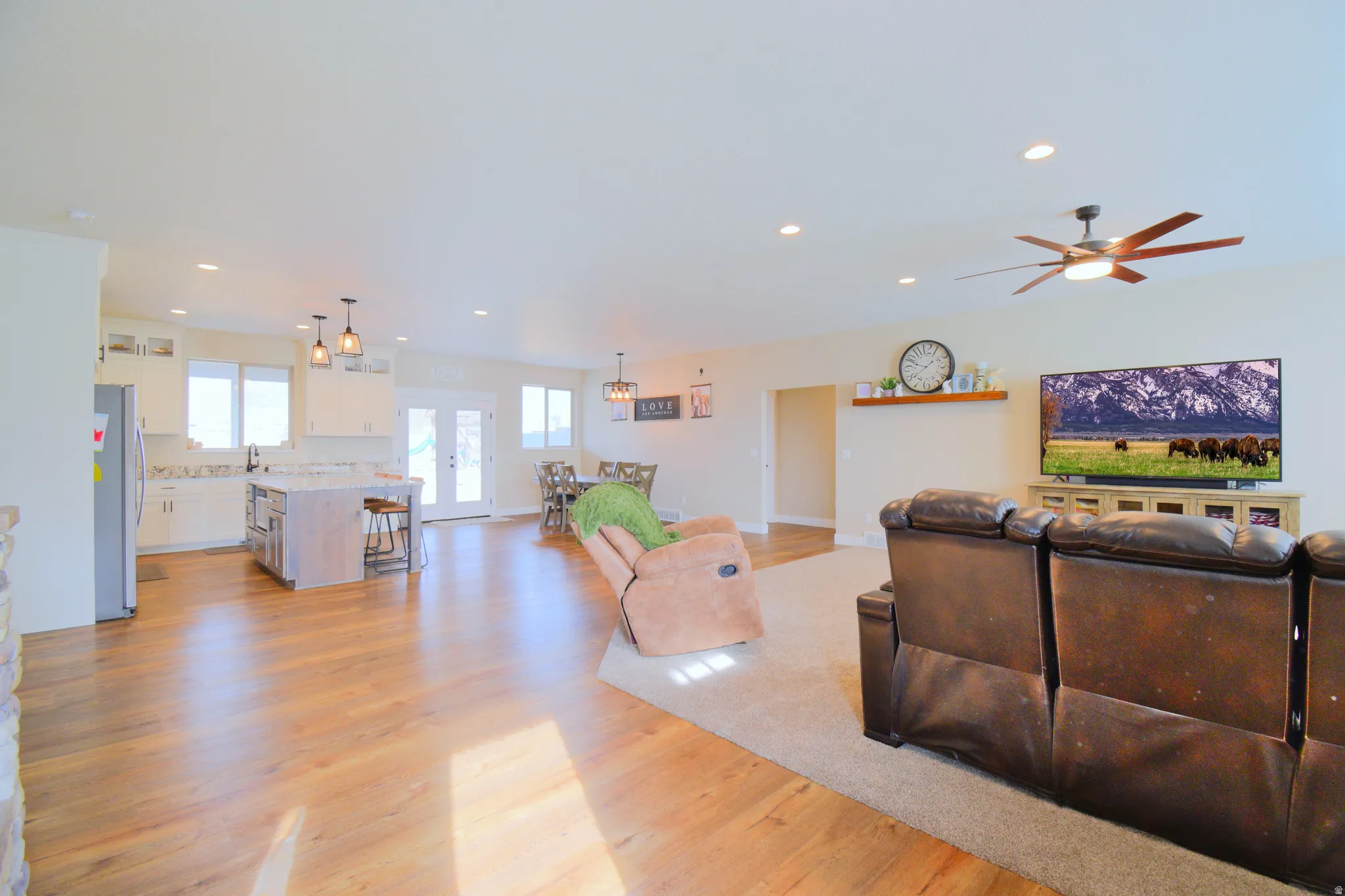 Living area with light wood finished floors, suspended lighting, and ceiling fan