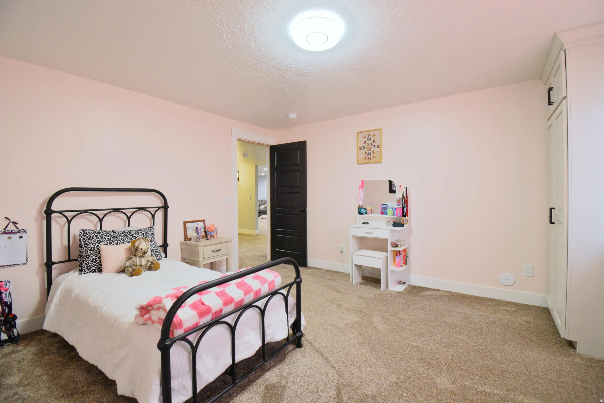 Bedroom with light colored carpet and a textured ceiling