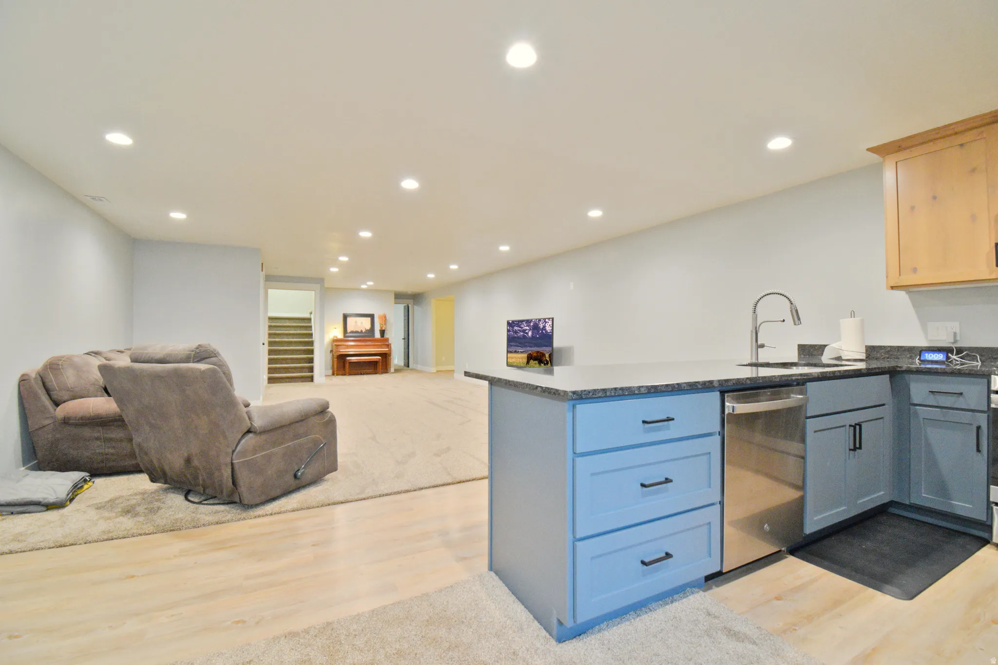 Kitchen with a peninsula, open floor plan, light wood-style floors, dark stone counters, and recessed lighting