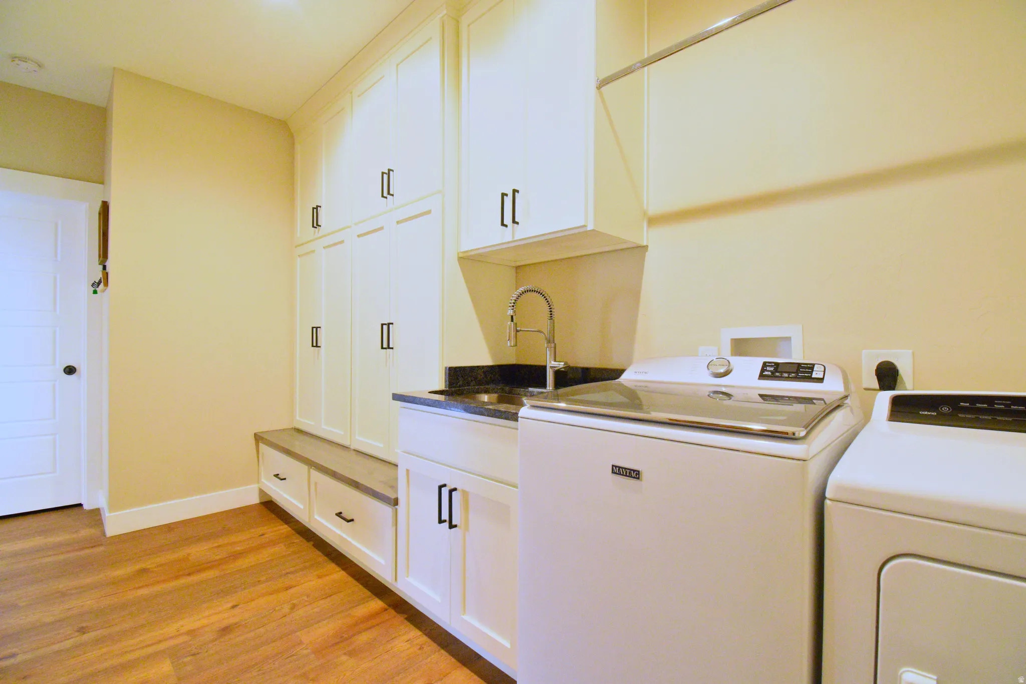 Laundry room with cabinet space, light wood-type flooring, and washing machine and clothes dryer