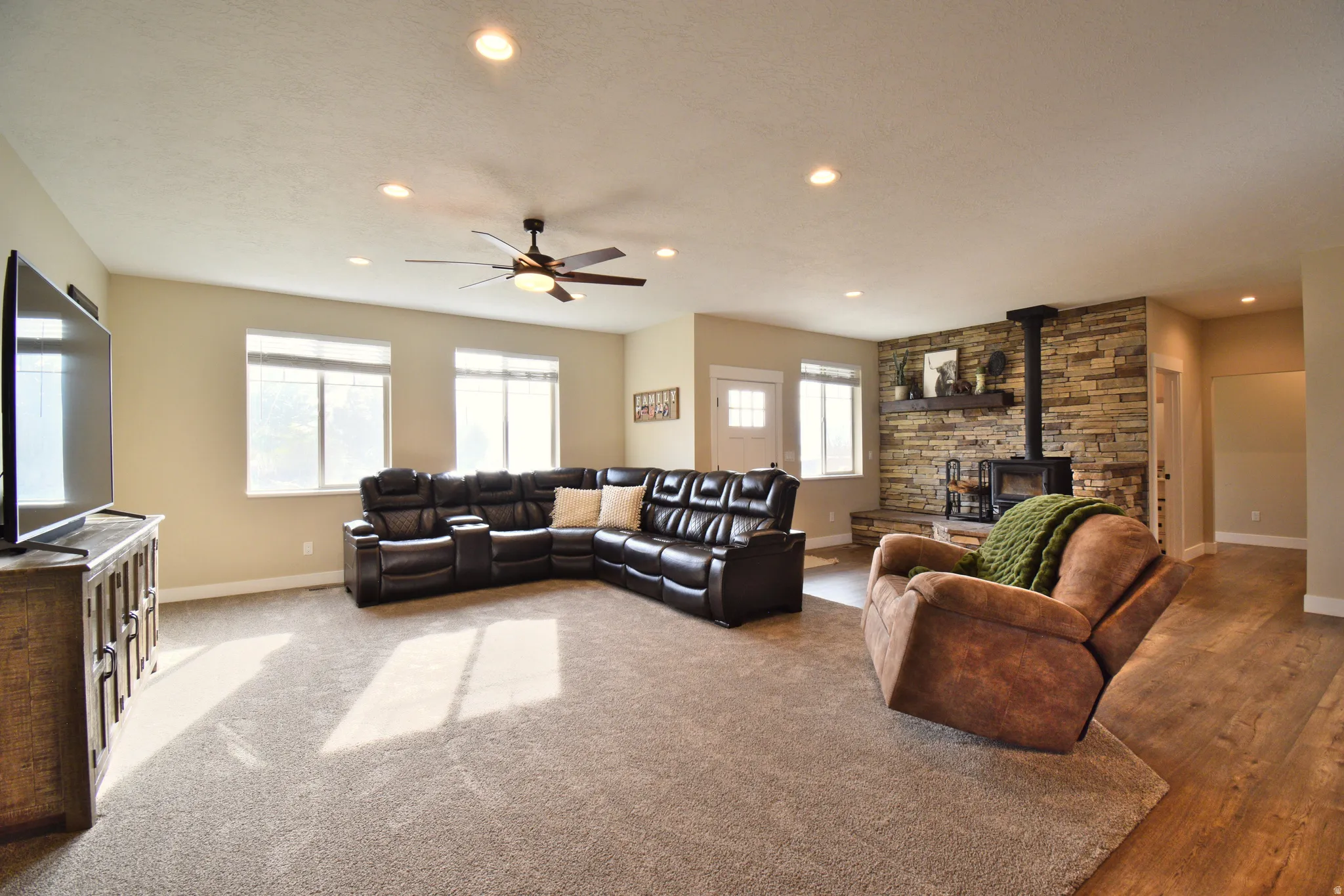 Living area with a wood stove, ceiling fan, and recessed lighting