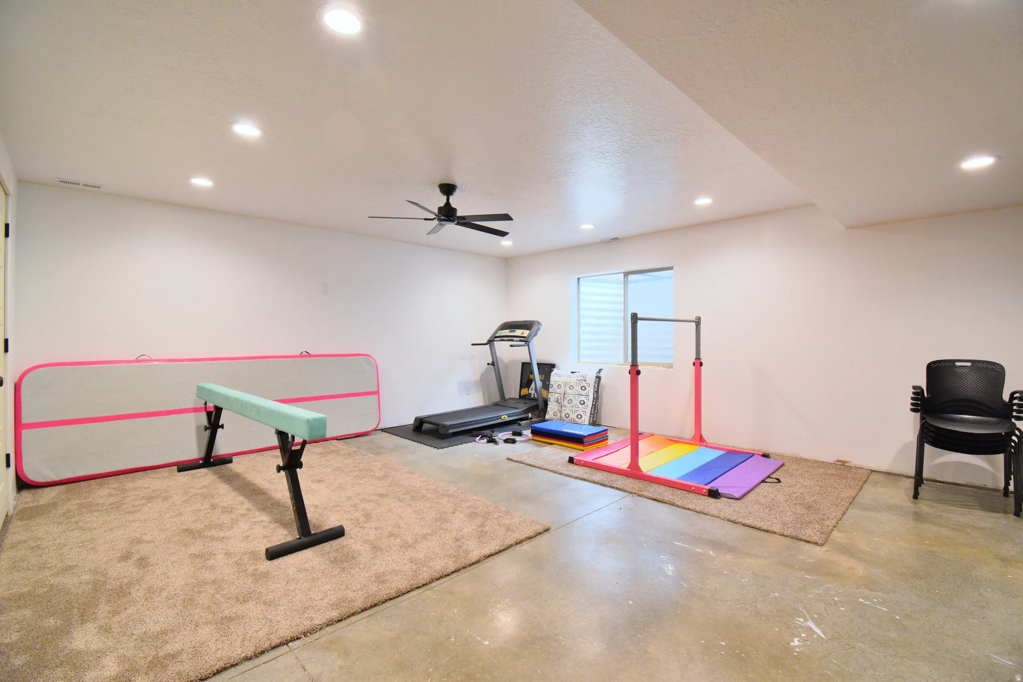 Exercise room with concrete flooring, a ceiling fan, and recessed lighting
