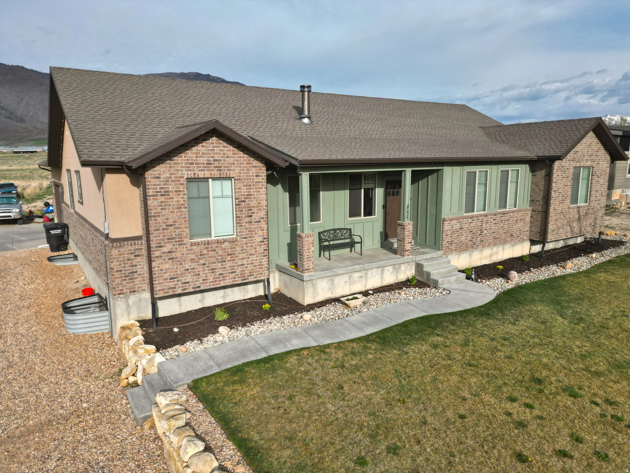 View of front of house with brick siding, a porch, a front yard, and roof with shingles