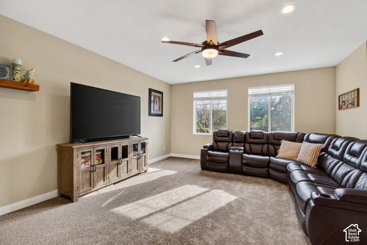 Carpeted living space with neutral painted walls and a ceiling fan with integrated lighting