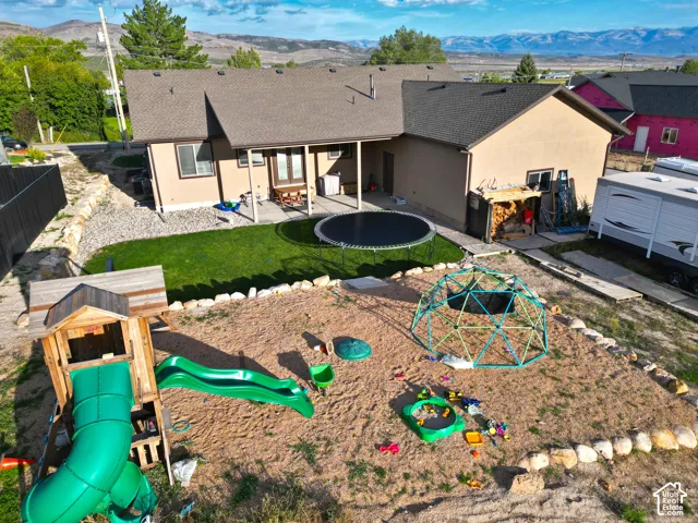 Rear exterior with a covered patio, artificial turf, and a gravel area