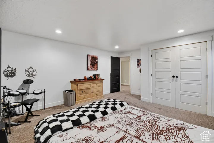 Recessed lighting illuminates the carpeted room, featuring white walls, a dark accent wall, and white five-panel bifold closet doors with dark hardware