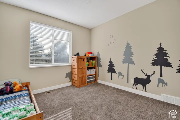 Room featuring neutral wall paint, a large window with blinds, and textured carpeting