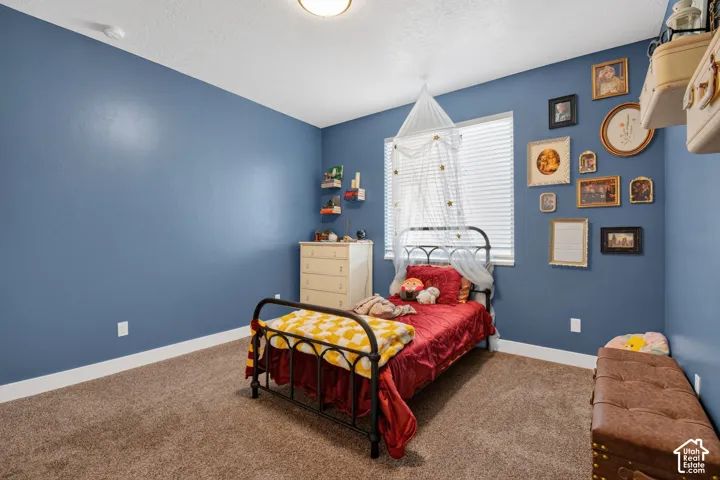 Spacious room featuring blue wall paint, plush carpet flooring, and white baseboards