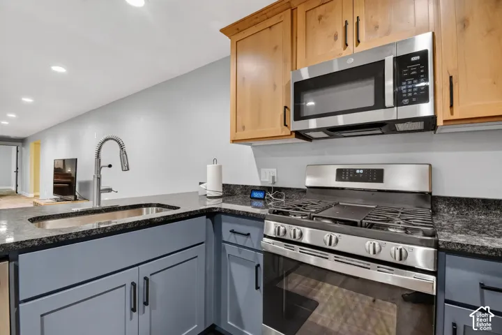 Kitchen featuring stainless steel appliances, granite countertops, two-tone cabinetry, recessed lighting, and a gooseneck faucet