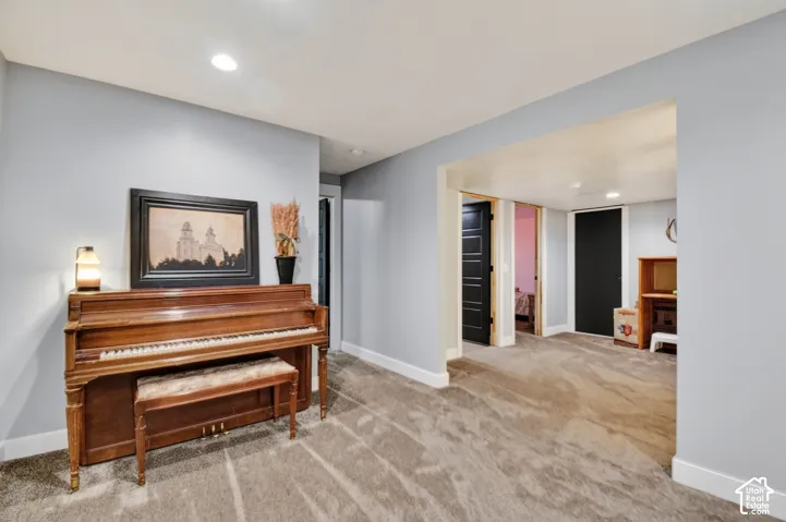 Carpeted interior space featuring light blue walls, white trim, recessed lighting, and a broad entryway