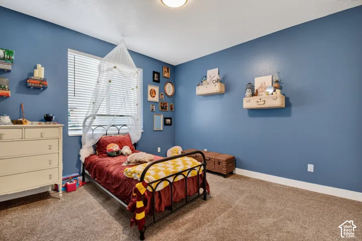 Spacious room featuring blue walls, window with blinds, recessed ceiling light, and neutral carpet flooring