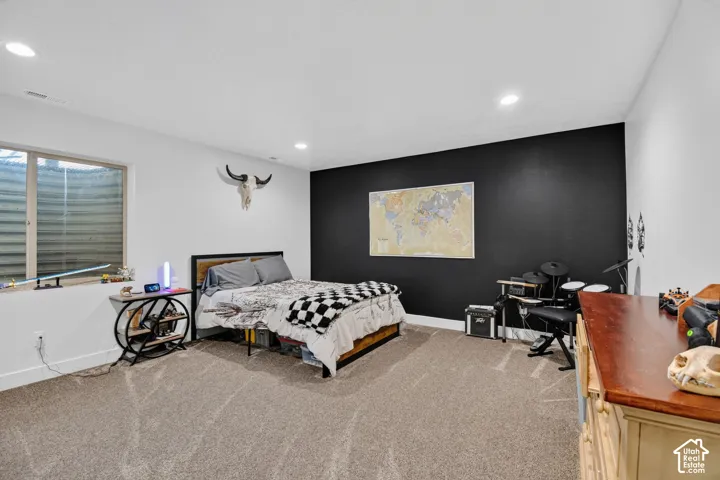 Spacious room featuring neutral carpet flooring, recessed ceiling lighting, a prominent black accent wall, and a large window with horizontal blinds