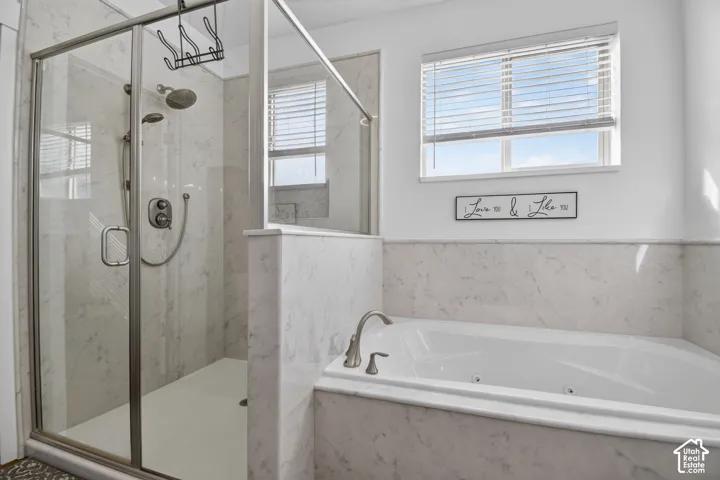 Shower-tub combination featuring a glass-enclosed shower with multiple showerheads and a built-in jetted tub