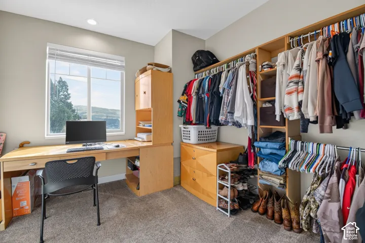 Flexible room featuring an integrated desk, expansive window, recessed lighting, and carpeting