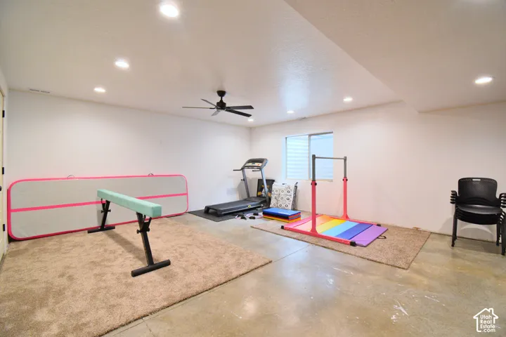 Exercise room with concrete flooring, a ceiling fan, and recessed lighting