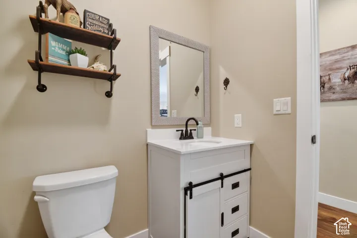 Bathroom featuring a white vanity with barn door style hardware, a white sink, and a black faucet