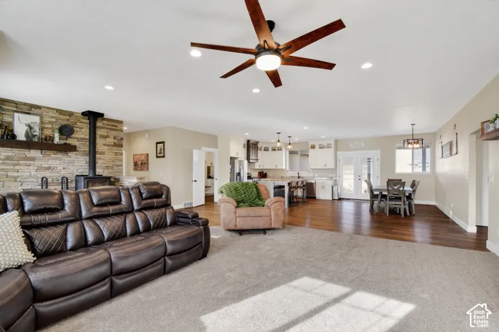 Spacious living area featuring a stone accent wall with a built-in wood stove, recessed lighting, and a contemporary ceiling fan