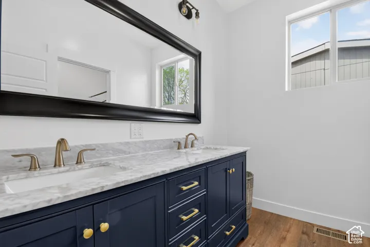 Dual vanity featuring a navy blue base cabinet with gold-toned hardware, undermount sinks, a light-toned countertop, and brass-finish faucets