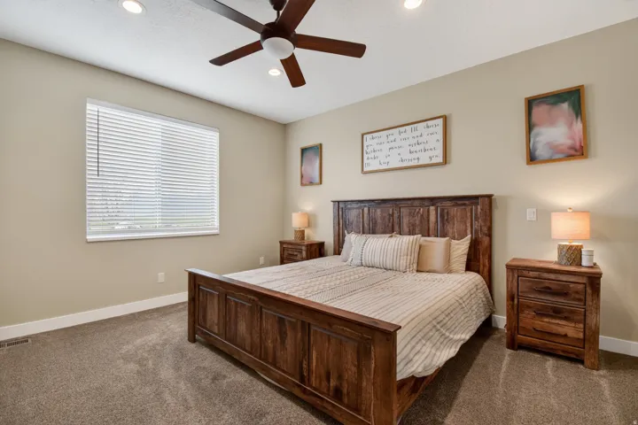 Recessed lighting and a ceiling fan illuminate this carpeted room, featuring a window with horizontal blinds