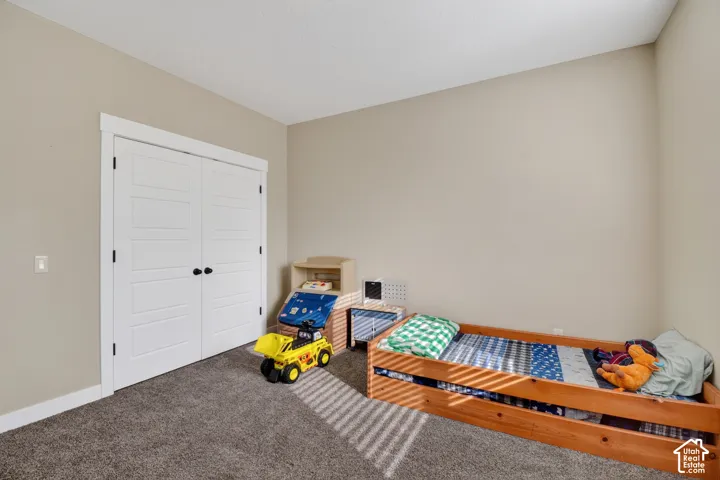 Spacious room featuring neutral wall tones, plush gray carpeting, and white bi-fold closet doors with matte black hardware