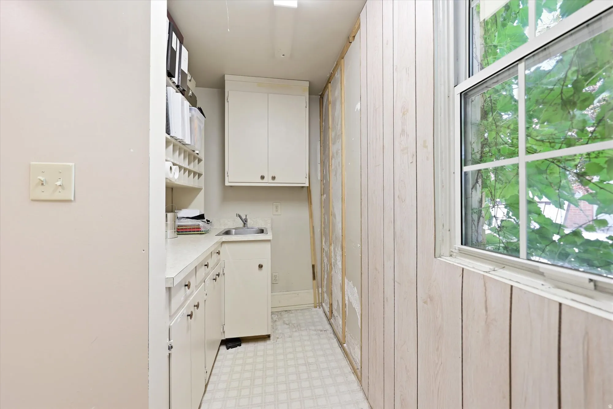 Utility area featuring a window, built-in cabinetry, a countertop, and a sink