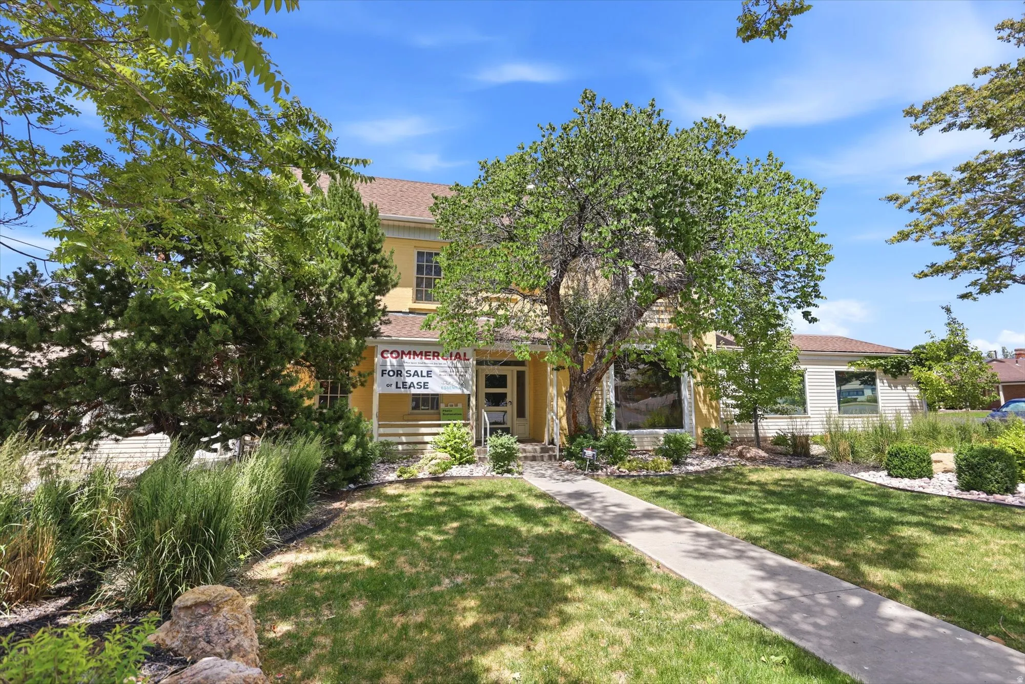 Two-story yellow stucco exterior with a brown shingle roof