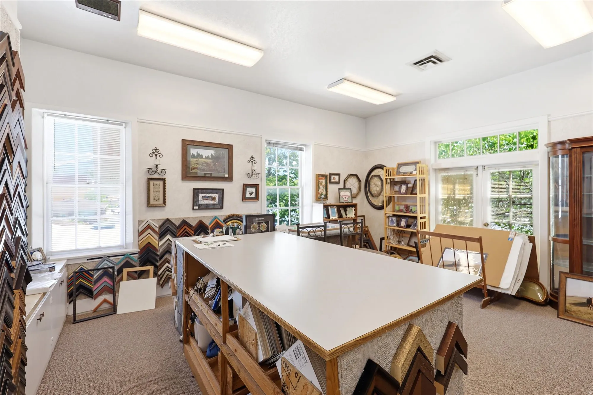 Spacious commercial interior featuring a large central work surface, multiple windows, and recessed lighting