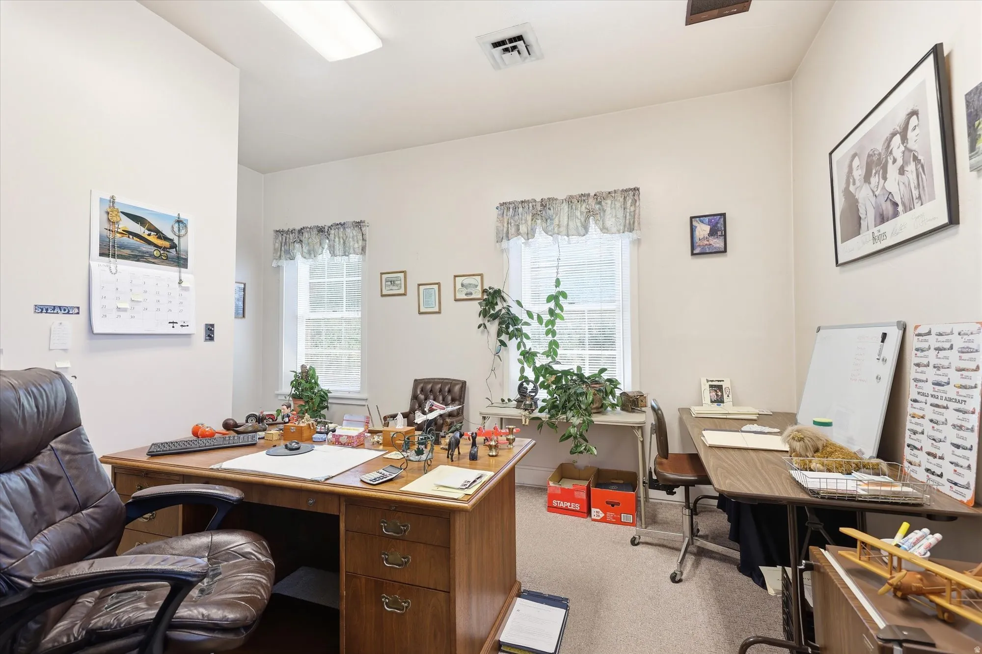 Versatile room featuring two windows, neutral carpeting, and overhead fluorescent lighting