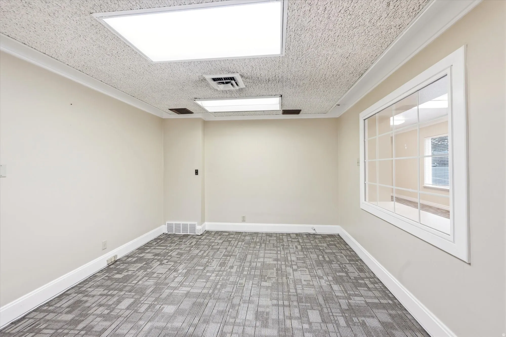 Interior space featuring recessed rectangular ceiling lighting, crown molding, and a patterned carpet