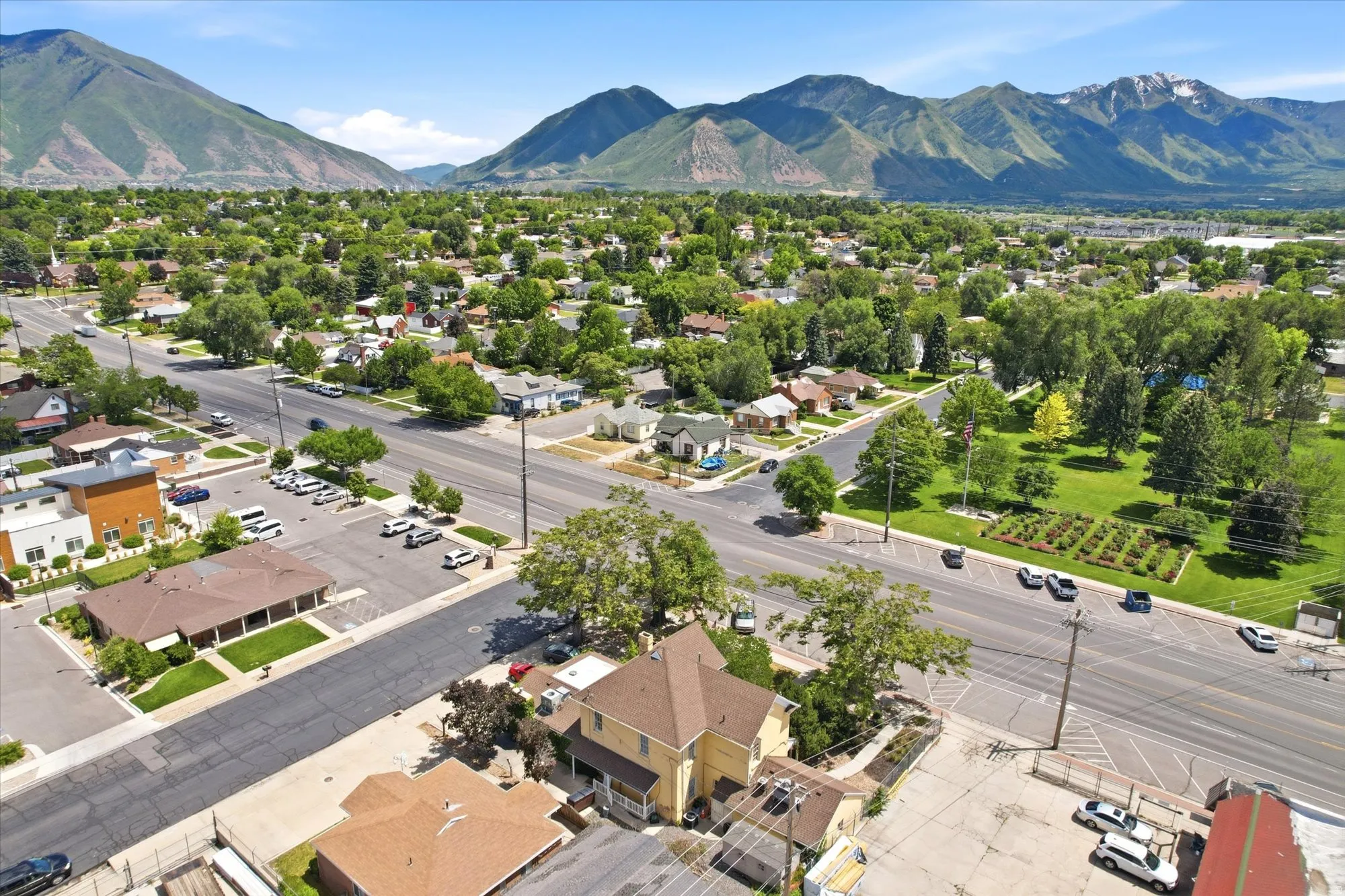 Expansive neighborhood setting featuring mature trees, a manicured park space, and a mountainous backdrop