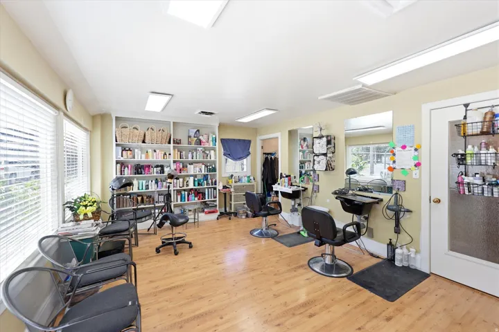 Open-concept commercial space featuring wood-finish flooring, multiple windows with blinds, recessed lighting, and built-in shelving